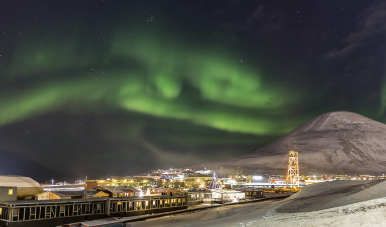 Nordlyset danser over Longyearbyen. Tårnet til høyre tilhører den gamle taubanen til gruvene © Sophie Cordon 